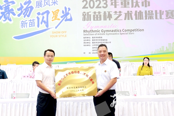 重庆市沙坪坝区体育局党组书记、局长黄华东先生为渝中区中华路小学授予“重庆市艺术体操后备人才训练基地”荣誉牌。李晓慧 摄